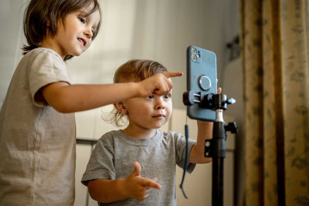 Two blogger brothers record videos on their phone using a tripod. Children and modern technologies